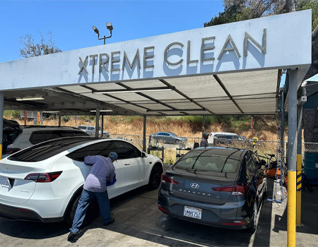 Fashion Square Car Wash attendants hand-drying customer vehicles under the Xtreme Clean canopy