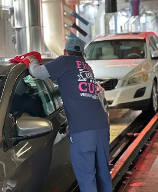 Fashion Square Car Wash detailer hand-drying a customer's car at the wash exit
